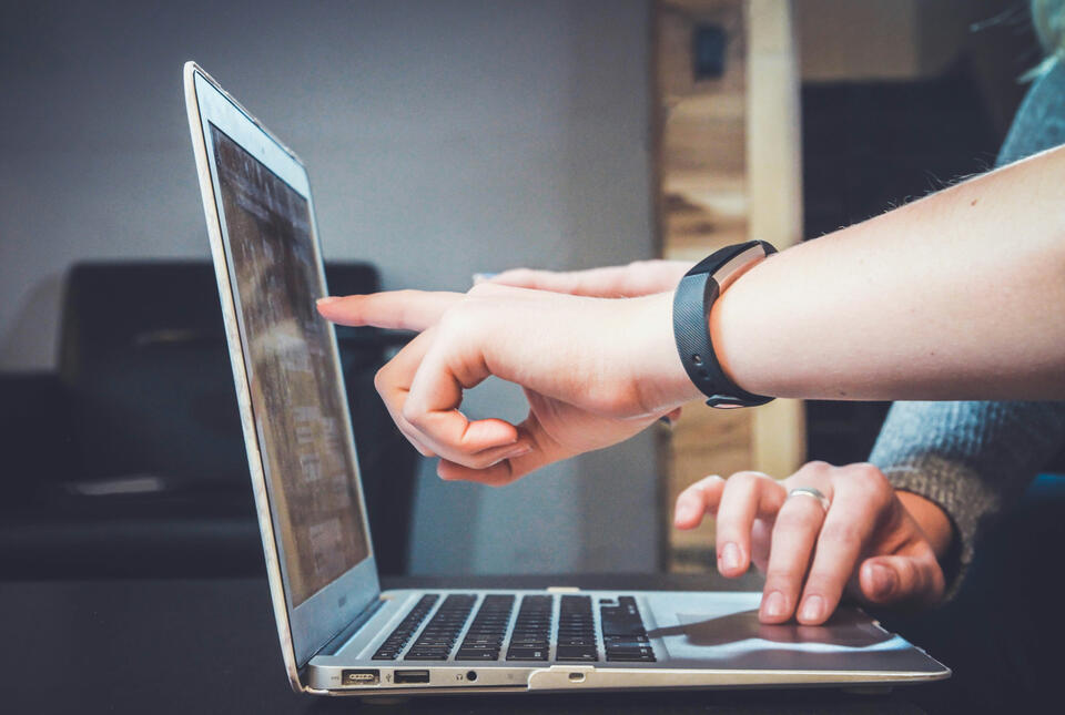 Hands pointing at a laptop screen